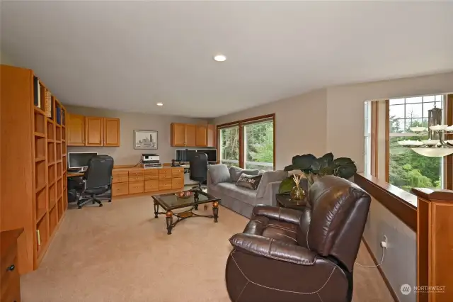 The upper level offers an open loft/work area complete with cabinets, bookshelves, and two workstations.
