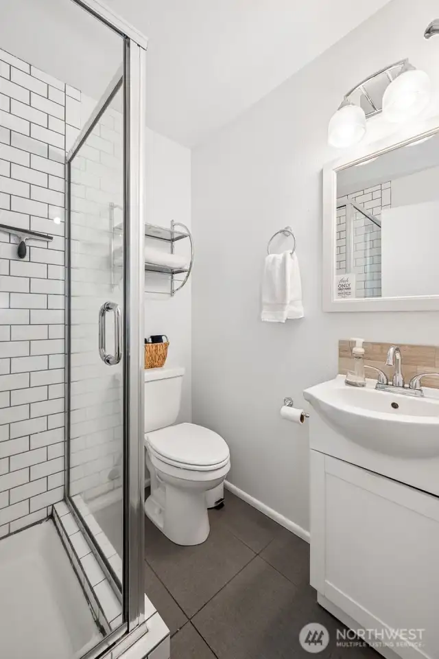 This primary suite bathroom keeps it simple yet sleek with dark tile floors, crisp white subway tile, and a glass shower. The single basin sink vanity adds a streamlined touch that makes every morning feel fresh.