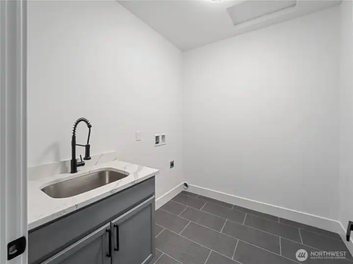 Upstairs laundry room with mud sink & tile floors.