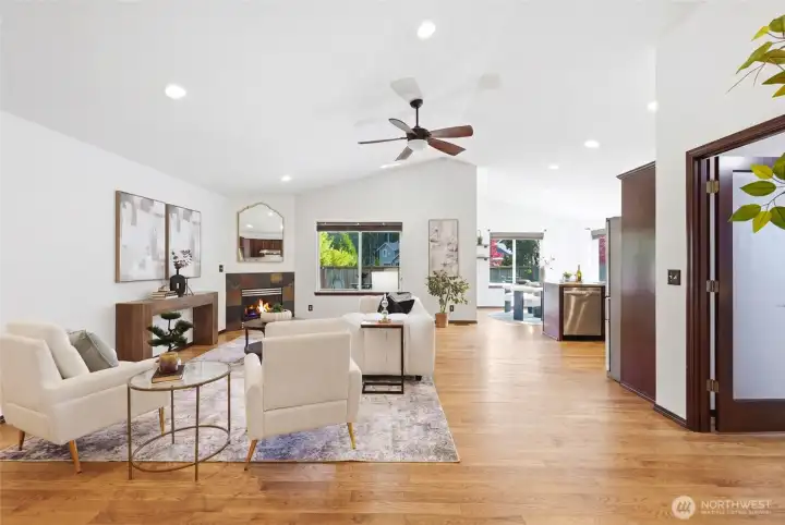 Bright, open living area with hardwood floors, a cozy fireplace, and easy flow into the kitchen and dining spaces.