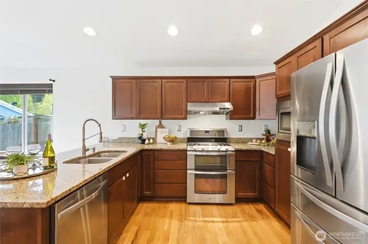 Kitchen with stainless steel appliances, granite counters, alder cabinets, and ample cabinet space.