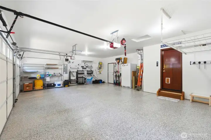 Organized 3-car garage with custom storage, large fridge, and direct access to the backyard.