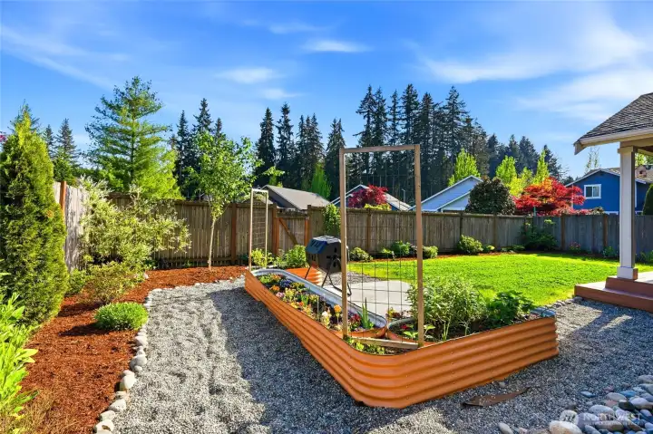Raised garden beds, gravel pathways, and thoughtful landscaping create a functional outdoor setup.