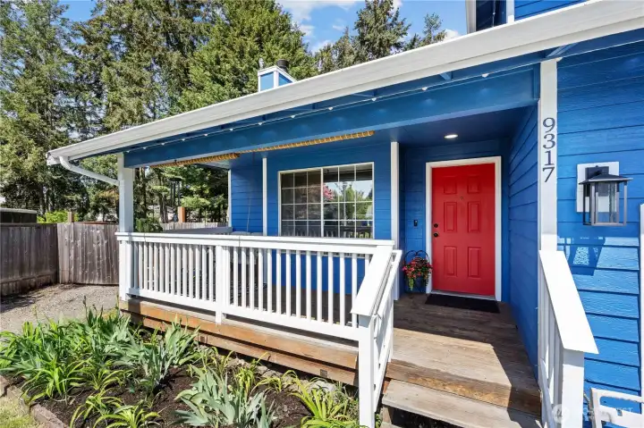 Covered White Painted Front Porch with Bright Red Door. 'Trimlight' style lights stay and offer easy event lighting at the home!