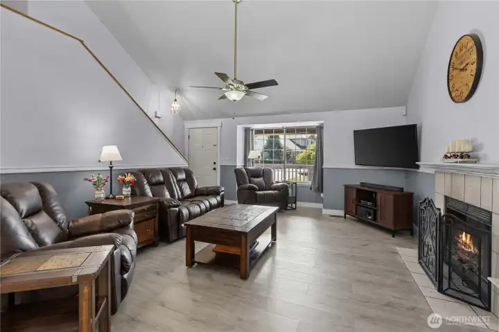 Living Room w/Vaulted Ceilings, Ceiling Fan, Wood-Burning Fireplace w/White Painted Mantle and Tile Surround plus Chair rail for beautiful accents.