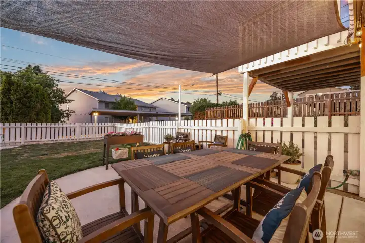 View of outdoor living and dining area and fenced backyard. View of outdoor living and dining area and fenced backyard.