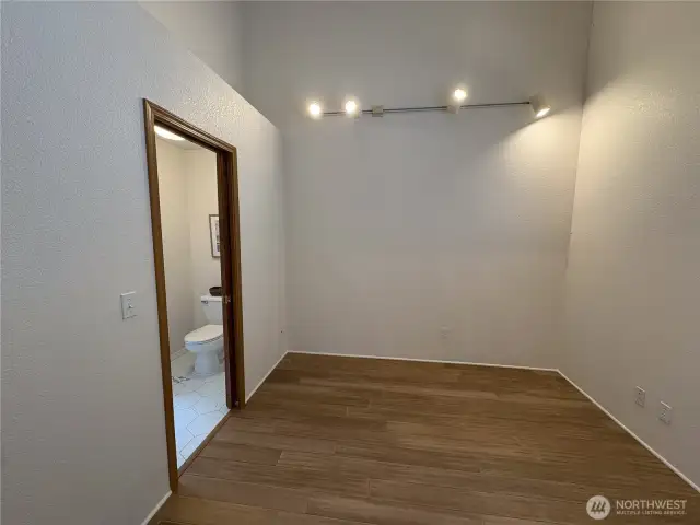 The second bedroom mirrors the primary with vaulted ceilings and modern directional lighting, while showcasing beautiful newly installed bamboo wood flooring for a warm, natural feel.