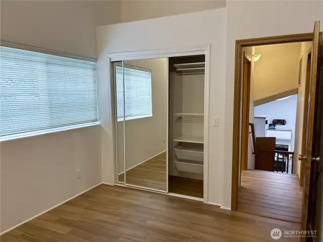 Mirrored closet doors and built-in organizer shelving make the most of the space—offering both function and style in this airy second bedroom.