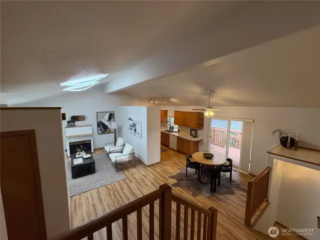 As you come down the stairs, take in the expansive vaulted ceilings that connect the entry, living, dining, and kitchen areas—creating a sense of light, space, and flow throughout the home.