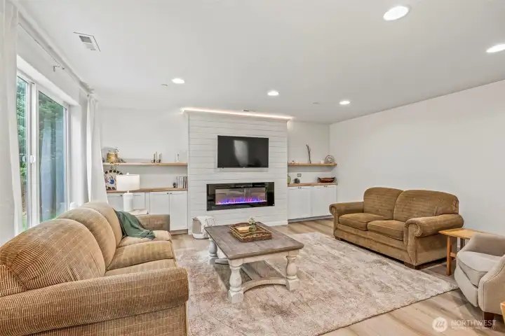 Gorgeous great room with uplighting, downlighting and fun fireplace LED lighting. Ship lap, life-proof flooring, beautiful floating shelves and built-in cabinetry...