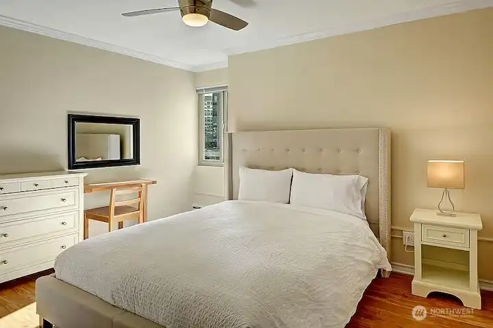 Tasteful primary bedroom with queen size bed, vanity, dresser, closet and ceiling fan.