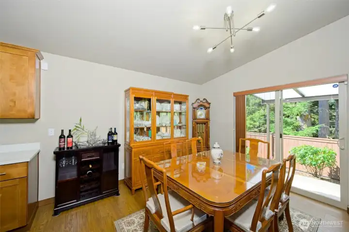 Dining room with luxury vinyl flooring, slider to the backyard, and a window behind the china cabinet.