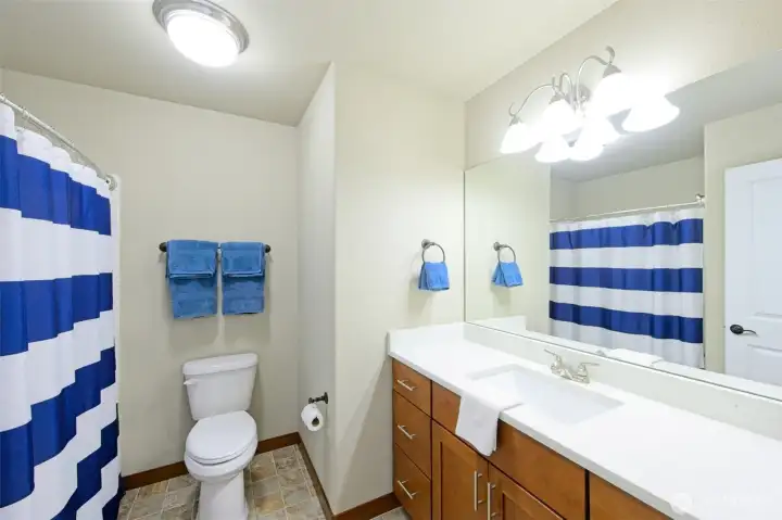Full main bathroom with Quartz countertops and cherry wood cabinets.