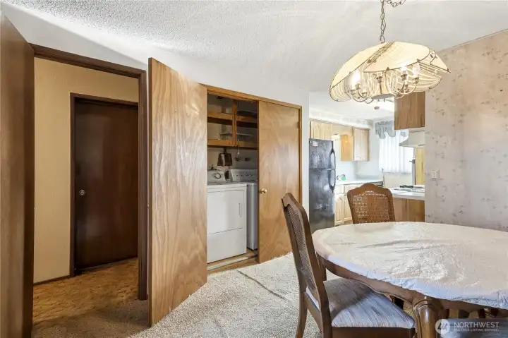 The laundry center is adjacent to the kitchen and with shelving for supplies