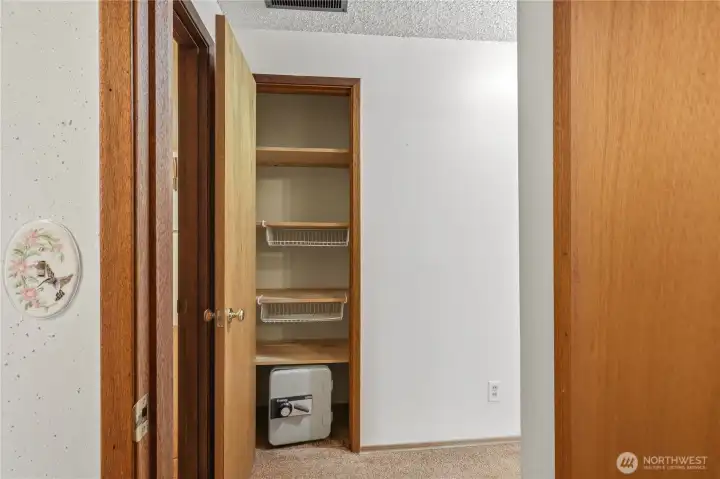 Linen closet with small floor safe in the hallway between the bedrooms and full bath