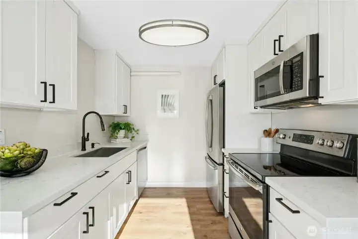 Renovated kitchen with crisp white cabinets, quartz countertops and stainless steel appliances.