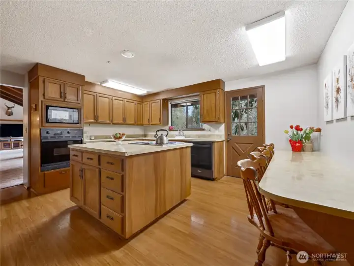 The kitchen boasts this beautiful cabinetry, center island, and a clever breakfast bar.