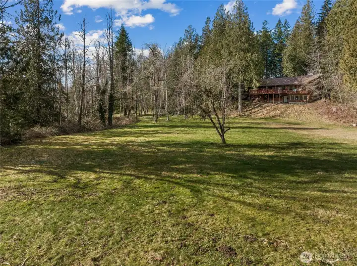 The large yard behind the home leads to the bridge that goes to the rest of the property.