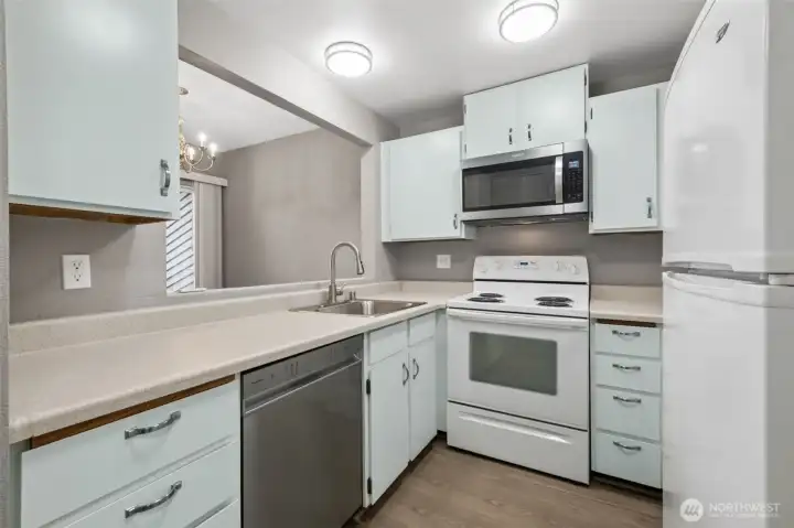 The freshly painted kitchen is open to the dining space and features updated lighting, new floors, a new microwave and dishwasher.