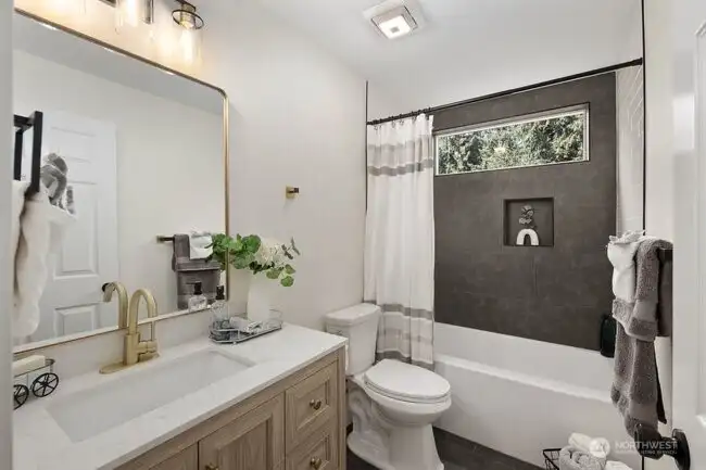 The total bathroom remodel boasts custom tile, new vanity, new quartz counters, fixtures, and even a bluetooth speaker!