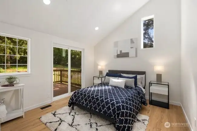 The primary bedroom with its vaulted ceiling, new slider to the private deck, and view of the backyard.