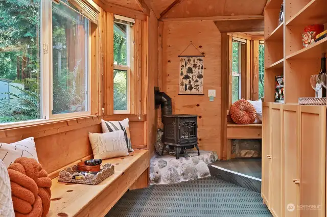 Your view as you turn left upon entry. This area used to be a wrap around porch and was finished and enclosed by previous owner. Built-in window seats are part of the charm! Freestanding propane stove warms up this space beautifully.