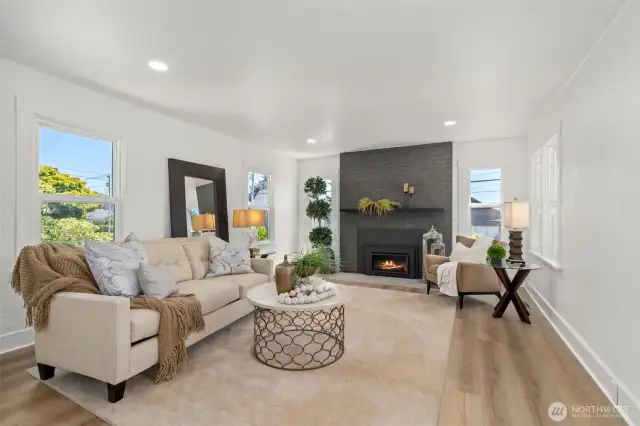 Spacious living room features a gas fireplace, new paint, floorin and lighting.