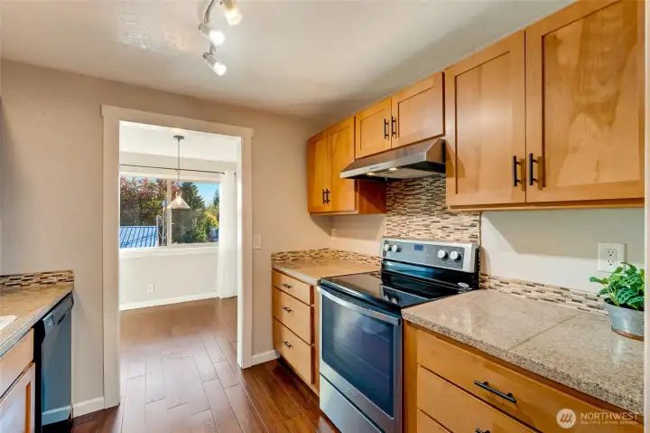 Galley kitchen with light wood and all black appliances give the kitchen beautiful contrast.
