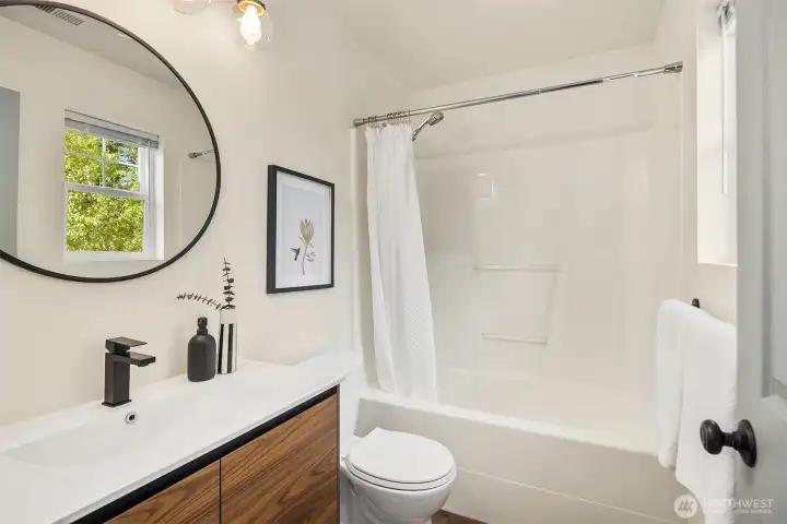 One of two full bathrooms on the upper level. This one is part of the primary suite.Updated with modern finishes.