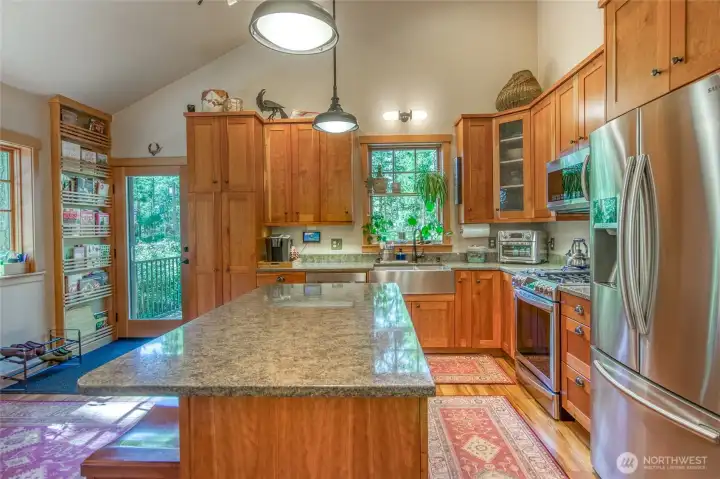 Custom cabinetry with soft close doors, wood doors and trim throughout. LED lighting, quartz countertop and stainless steel farmhouse sink with touchless faucet, built-in pull-out waste and recycling bin drawer, under cabinet lighting.