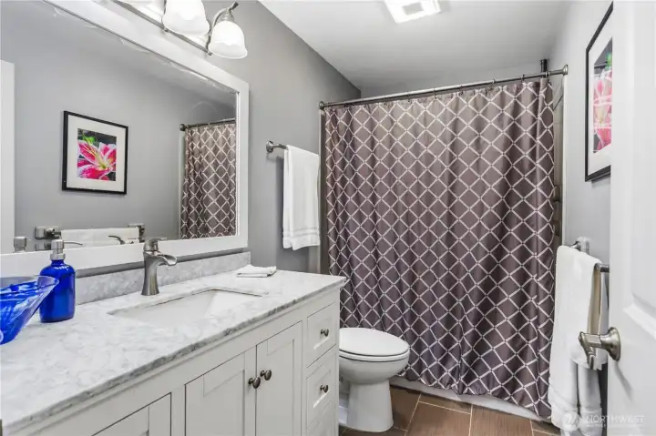 Hall full bathroom has a tub-shower and a tiled floor.