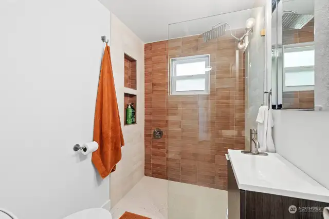 The stylish main floor bath offers a walk-in shower featuring a rain shower faucet, recessed storage cubbies and ceramic tile surround.