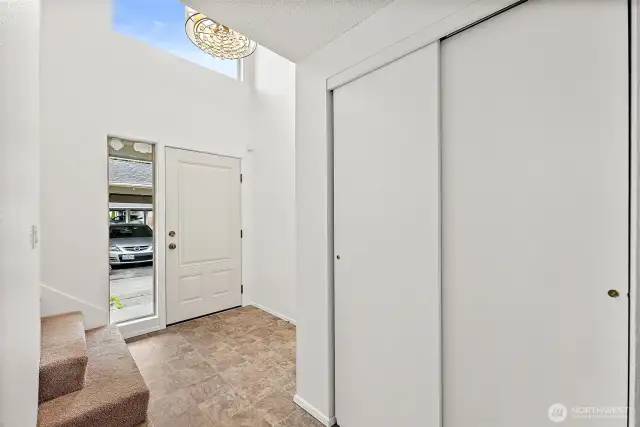 The entryway features a convenient coat closet for guests and soaring ceilings with windows that fill the space with natural light