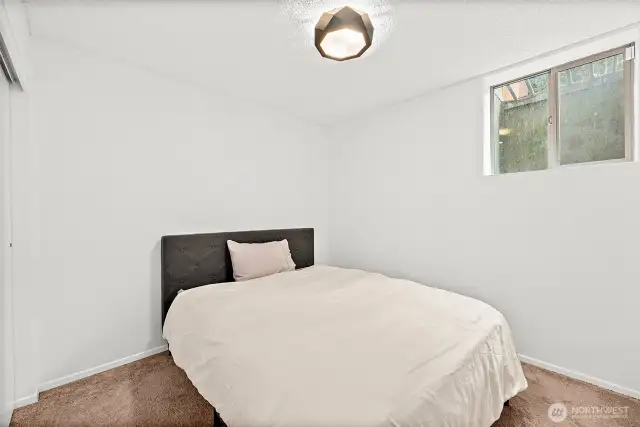 Lower-level Bedroom 1 features daylight windows and high ceilings, creating a bright and open atmosphere.