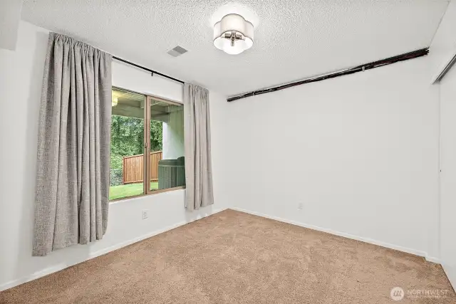 Lower-level Bedroom 2 boasts large windows overlooking the backyard’s lush greenery