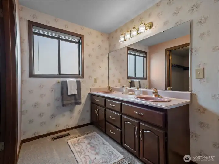 His and her vanities with pink sinks match the tiles and vintage soaking tub.