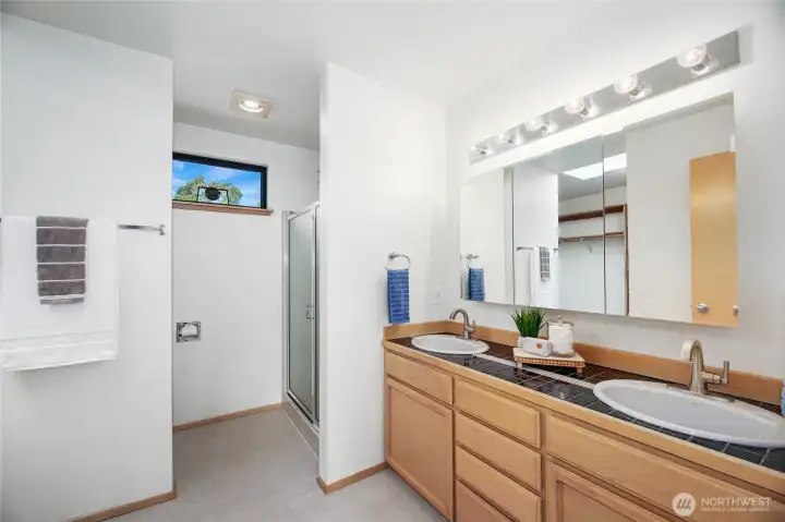 Primary bathroom with double vanity, shower and toilet around corner.