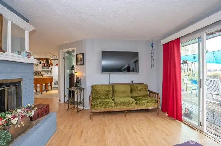 Living room with brick fireplace and sliding glass door to the big deck. The door leads to the primary bedroom with a 3/4 bathroom