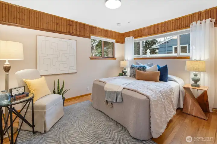 The 2nd bedroom retains its rustic feel, with hardwood floors and corner windows.
