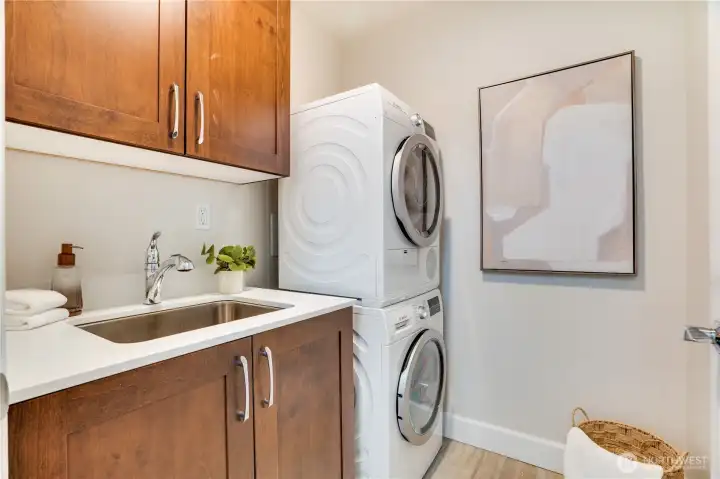 In unit laundry with utility sink and cabinet space.
