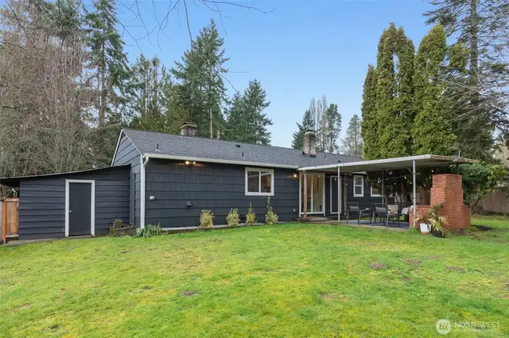 View of back of the home with covered patio and shed access.