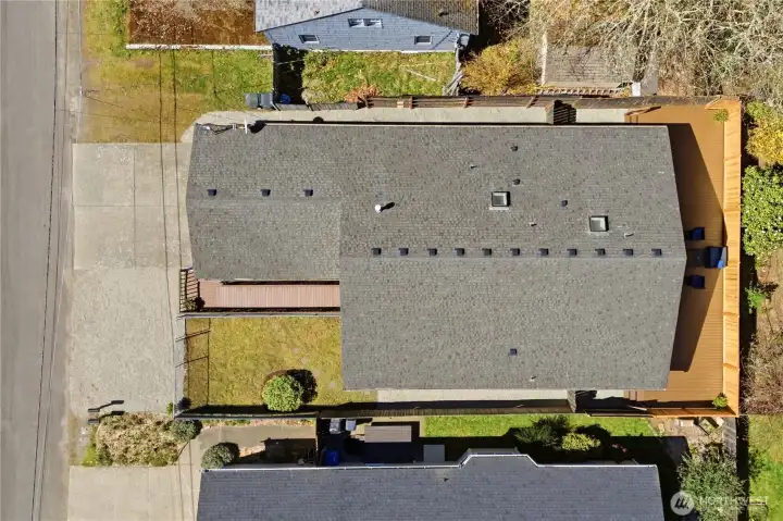 This bird's eye view of the property shows the clean roof, fenced perimeter, and spacious parking.