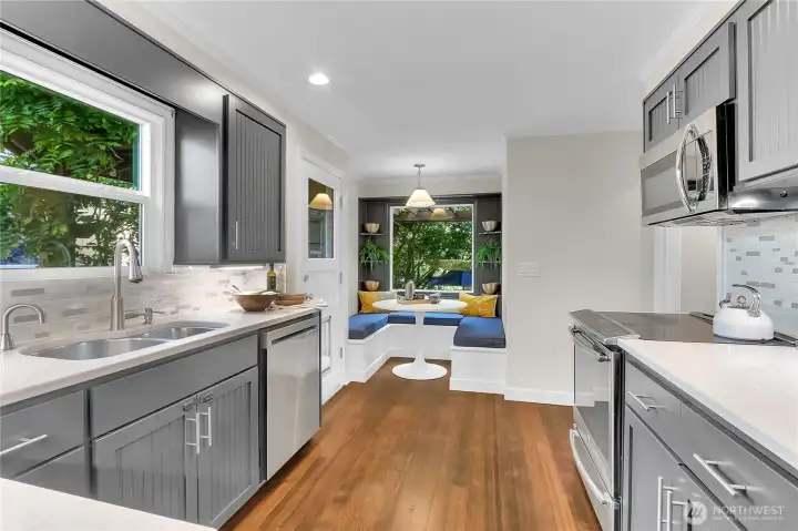 Super functional kitchen with backyard access to the left. Note the comfy kitchen nook, that overlooks the backyard; perfect spot for that morning coffee to get the day started. To the right of the stove is the hallway to bedrooms and bathroom, and lower level.