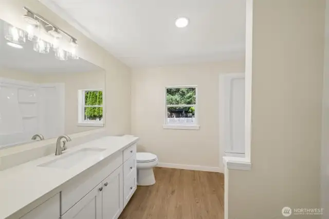 Primary bathroom with NEW flooring, trim, lighting, quartz countertops & shaker cabinets- plenty of countertop space!