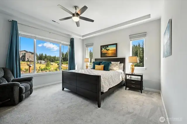 Bright and airy primary bedroom with picturesque windows overlooking the back yard and garden