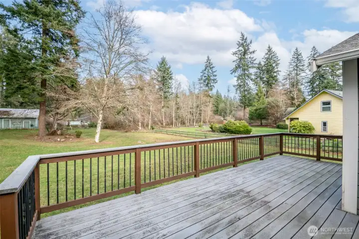 Expansive backyard, partially fenced with outdoor storage to the right of the deck.