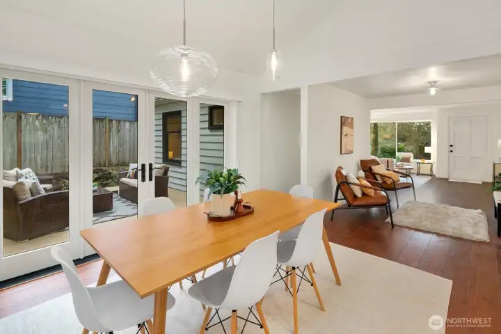 This bright living room was a thoughtful remodel with cathedral ceilings, surrounded by double paned windows, and designer lighting. French doors expand the interior living space to the deck and expansive back yard.