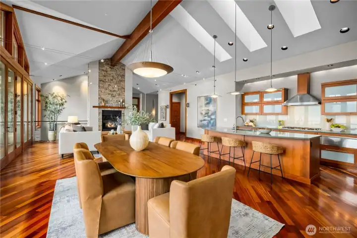Expansive open-concept kitchen, dining, and living with vaulted ceilings, skylights, and rich hardwood floors.