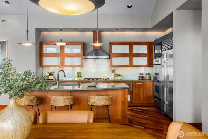 Chef’s kitchen with island seating, quartz countertops, custom cabinetry, and stainless steel appliances.