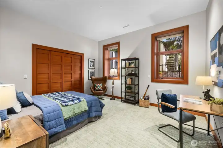 A generous, light-filled bedroom offering flexibility for work, rest, or play—complete with warm wood accents and serene natural outlooks.